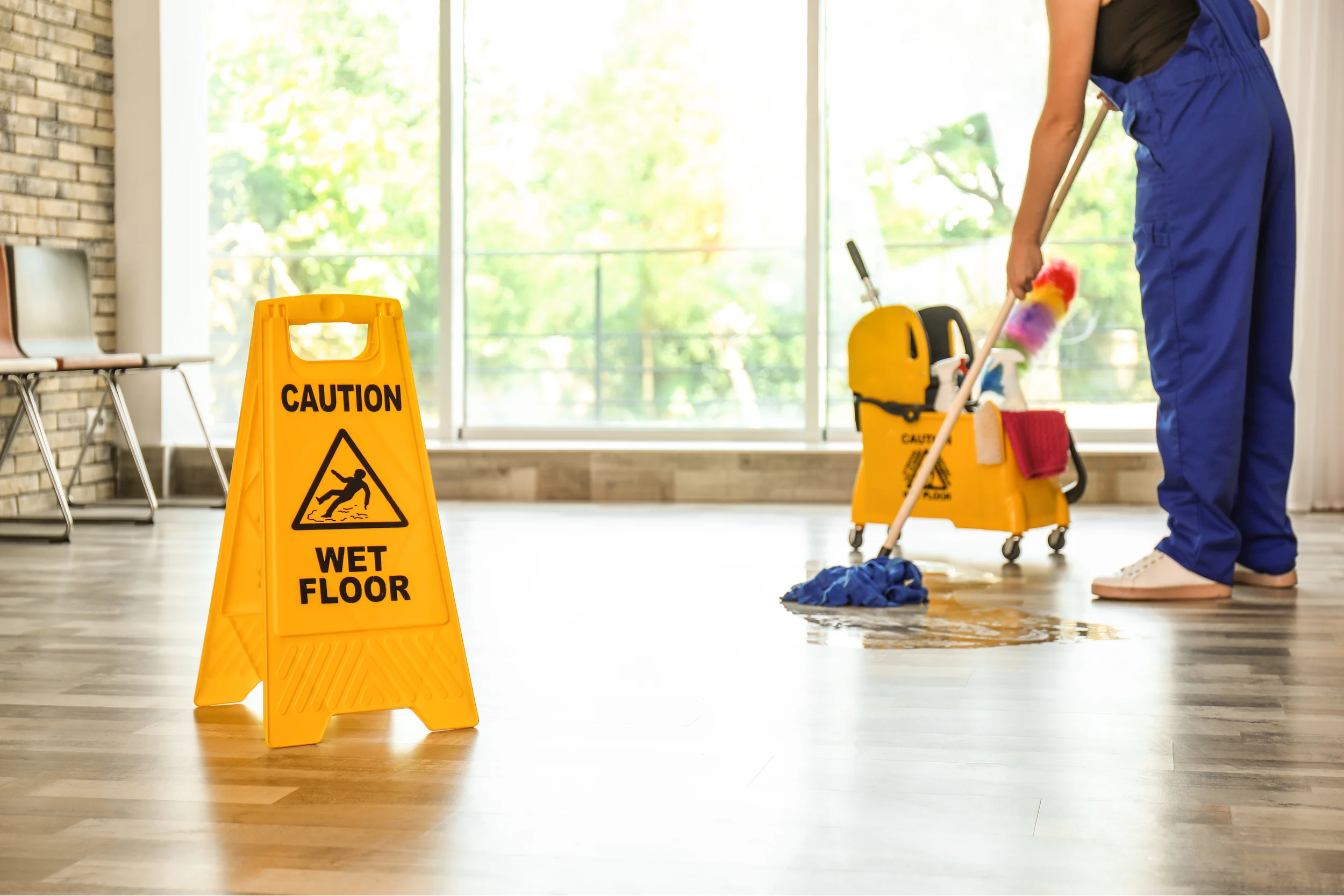 Person mopping floor with wet floor sign. Star Clean Ltd, Cleaning, Cleaners, Commercial Cleaners, Domestic Cleaners. Bath, Bristol
